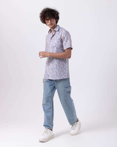 Man wearing a stylish blue abstract print slim fit half sleeve shirt, paired with casual pants for men's fashion.