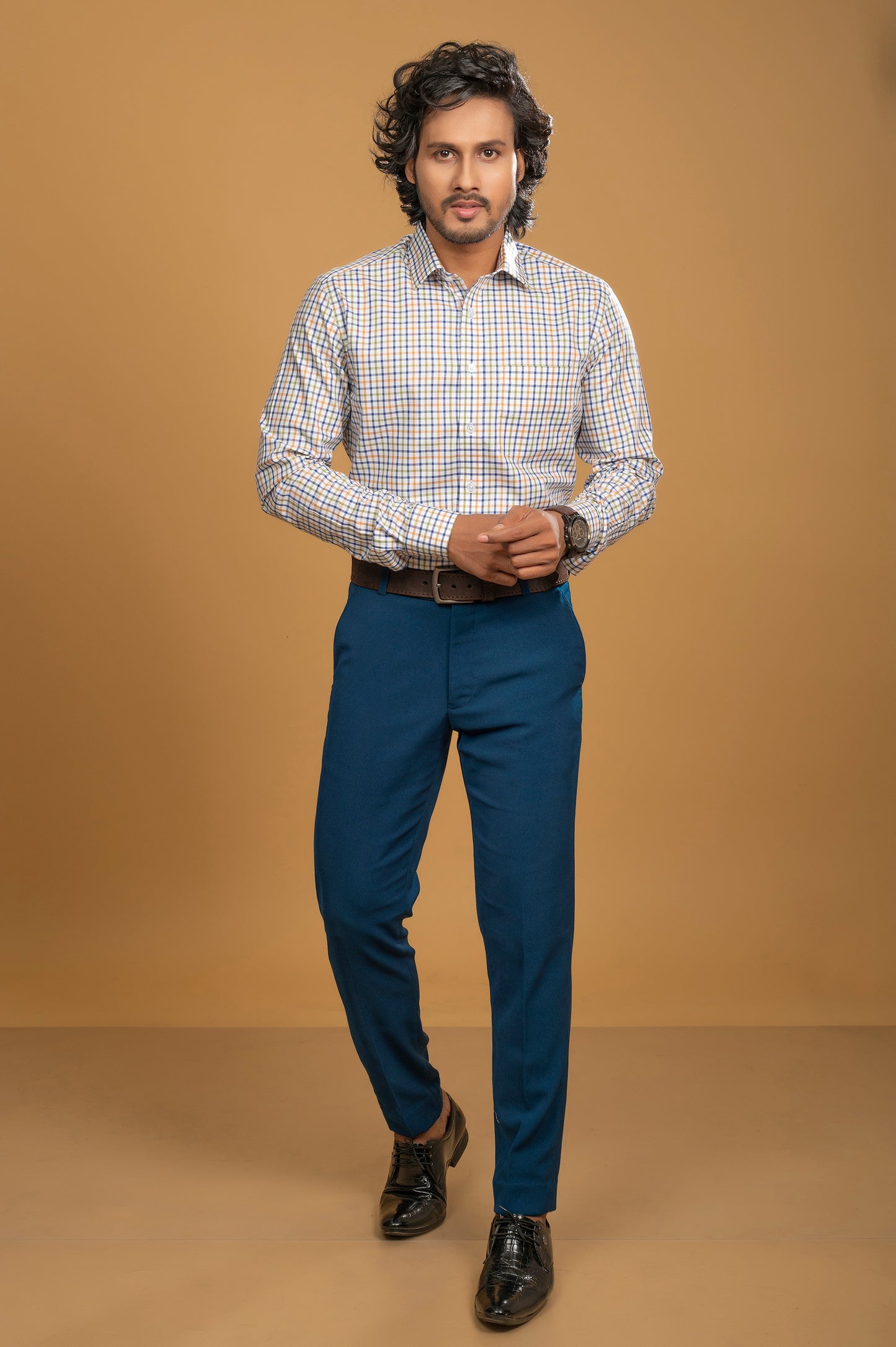 Model wearing a vibrant multicolor check shirt paired with blue trousers, showcasing modern men's fashion.