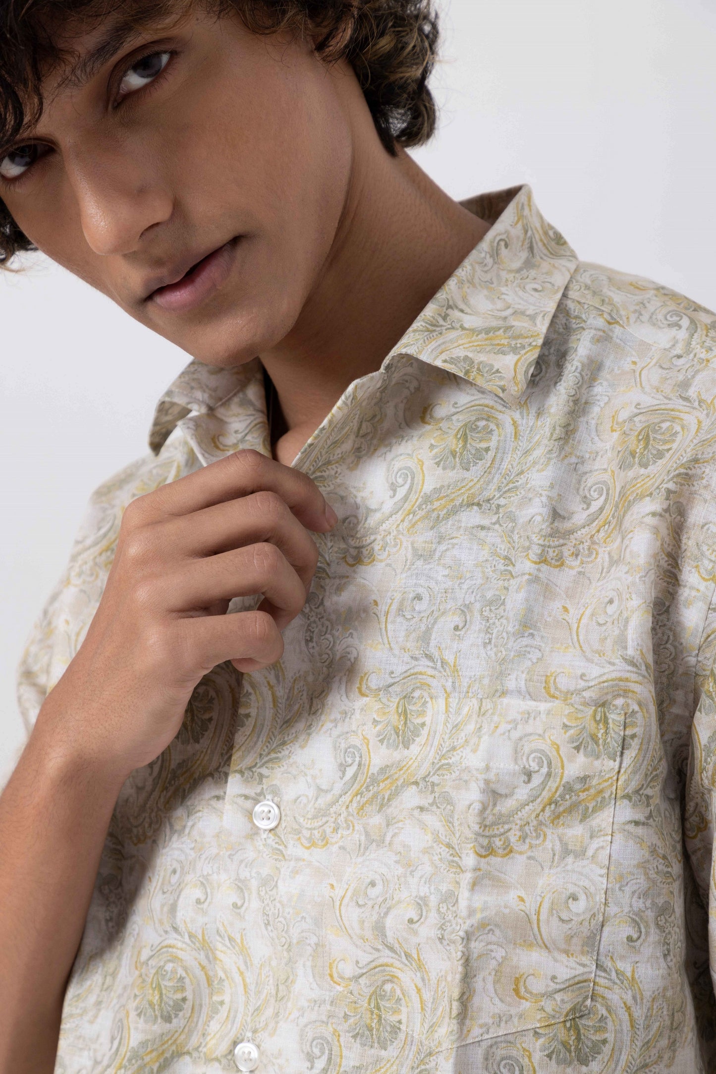 Close-up of a young man in a floral open collar regular print shirt, showcasing a relaxed, stylish look.
