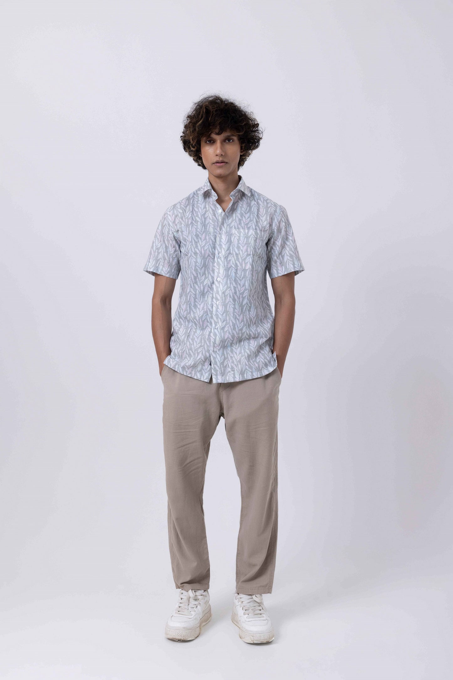 Model wearing a Leaf Print Down Collar Slim Fit Shirt in melange paired with casual beige trousers and sneakers.