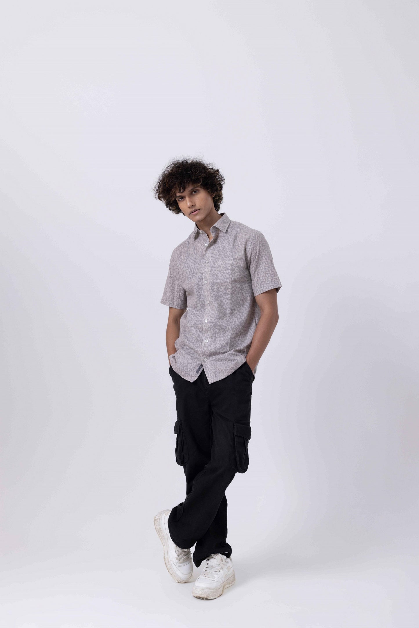 Model wearing a printed half sleeve shirt paired with casual cargo pants and sneakers, showcasing a modern style for men's shirts.