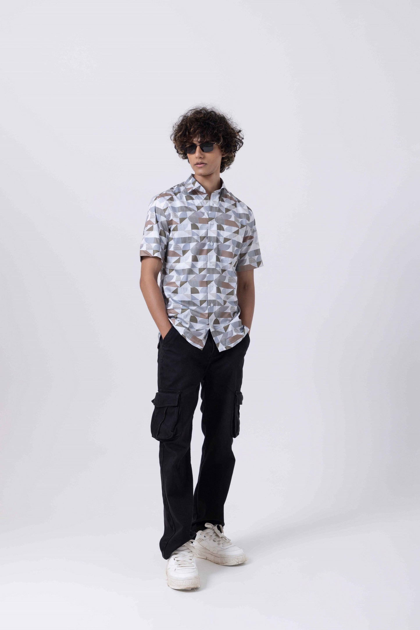 Man wearing The Man Printed Slim Fit Shirt with modern prints and black cargo pants.