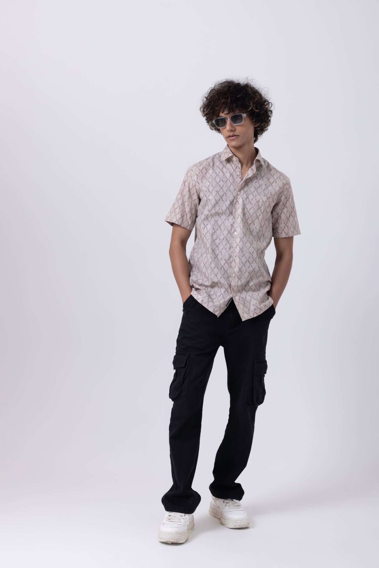 Stylish young man in patterned shirt and black cargo pants, showcasing modern fashion for casual outings.