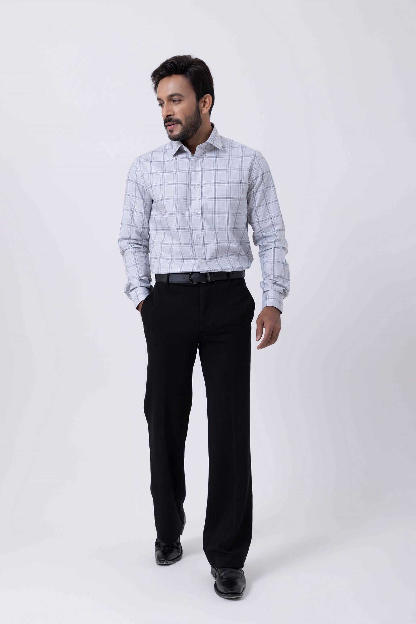 Man wearing Giza Classic Black and White Checked Regular Fit Shirt with black pants and shoes in a studio setting.