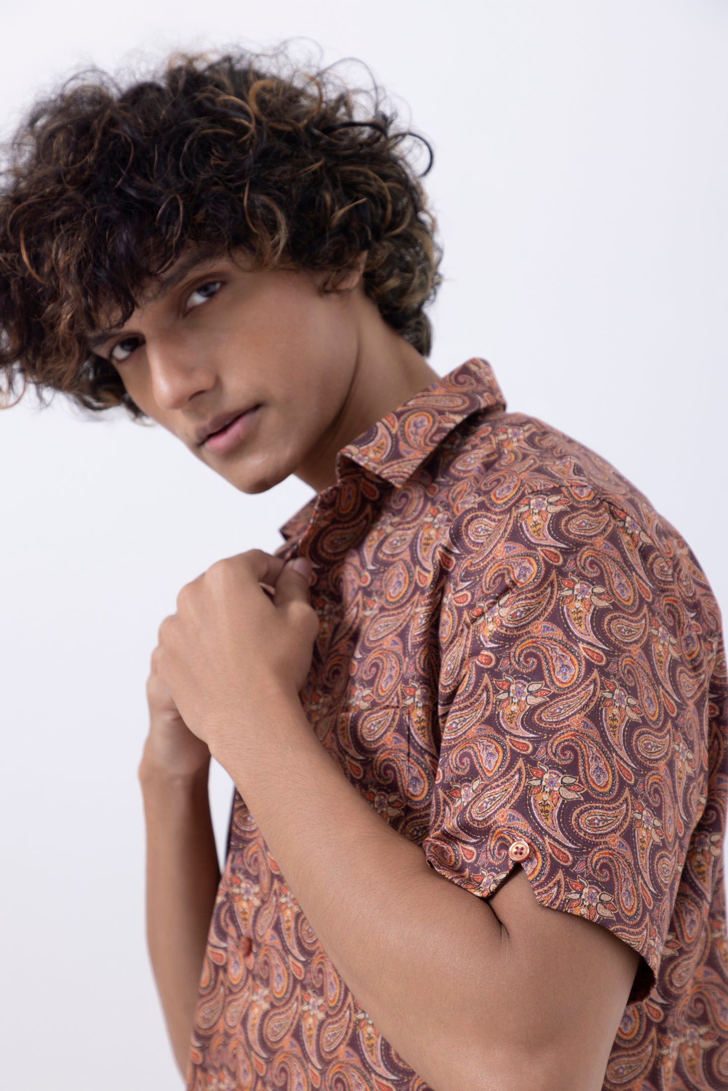 Model wearing a men's abstract print slim fit shirt in rust color with paisley design.