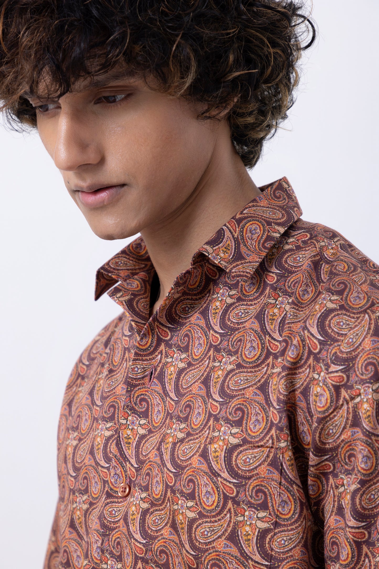 Close-up of a man wearing a paisley print men's shirt in rich rust color, showcasing modern style and comfort.