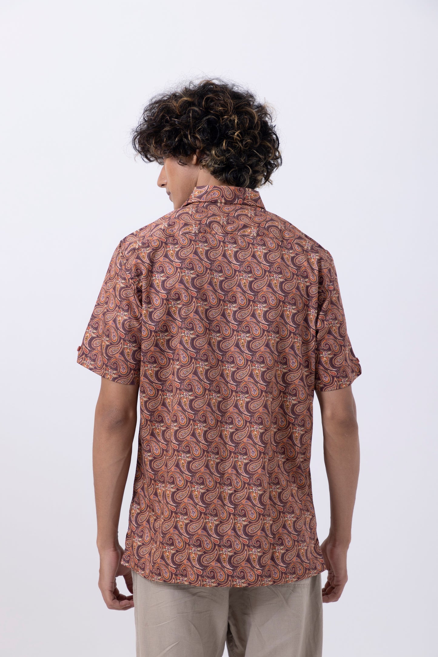 Back view of a man wearing a rust-colored abstract print slim fit shirt, showcasing unique style and comfort.