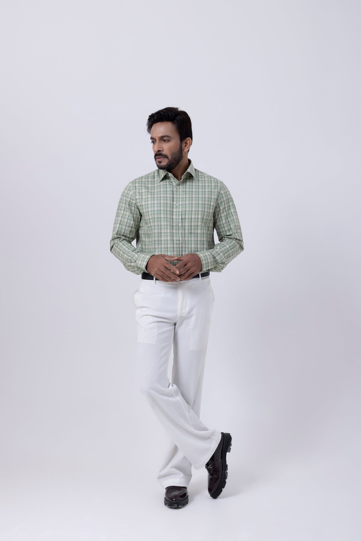 Man wearing an elegant white and green checkered shirt with white trousers, showcasing men's fashion style.