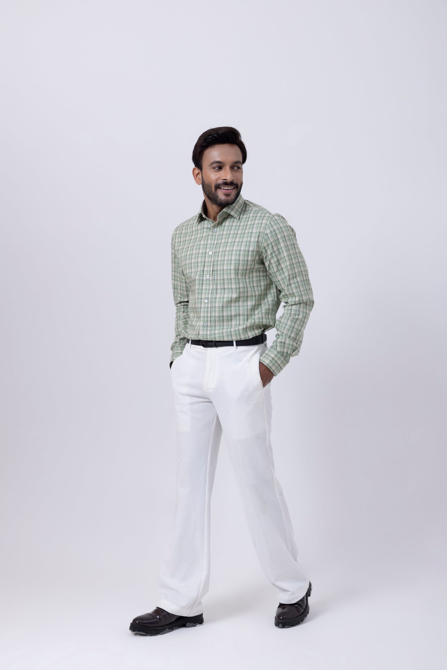 Man wearing a green and white checkered shirt with white pants, showcasing elegant men's fashion style.