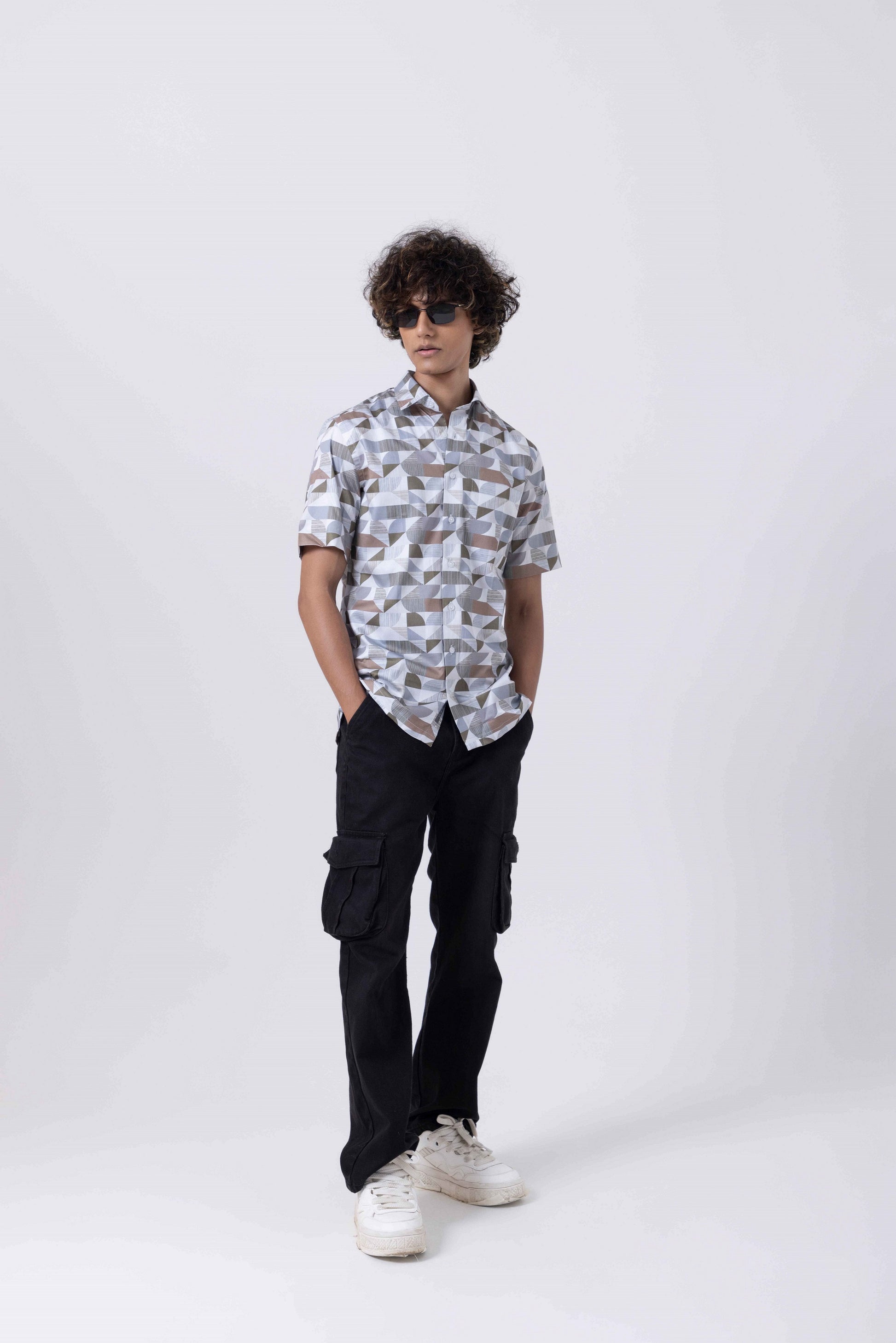 Man wearing The Man Printed Slim Fit Shirt with modern prints and black cargo pants.