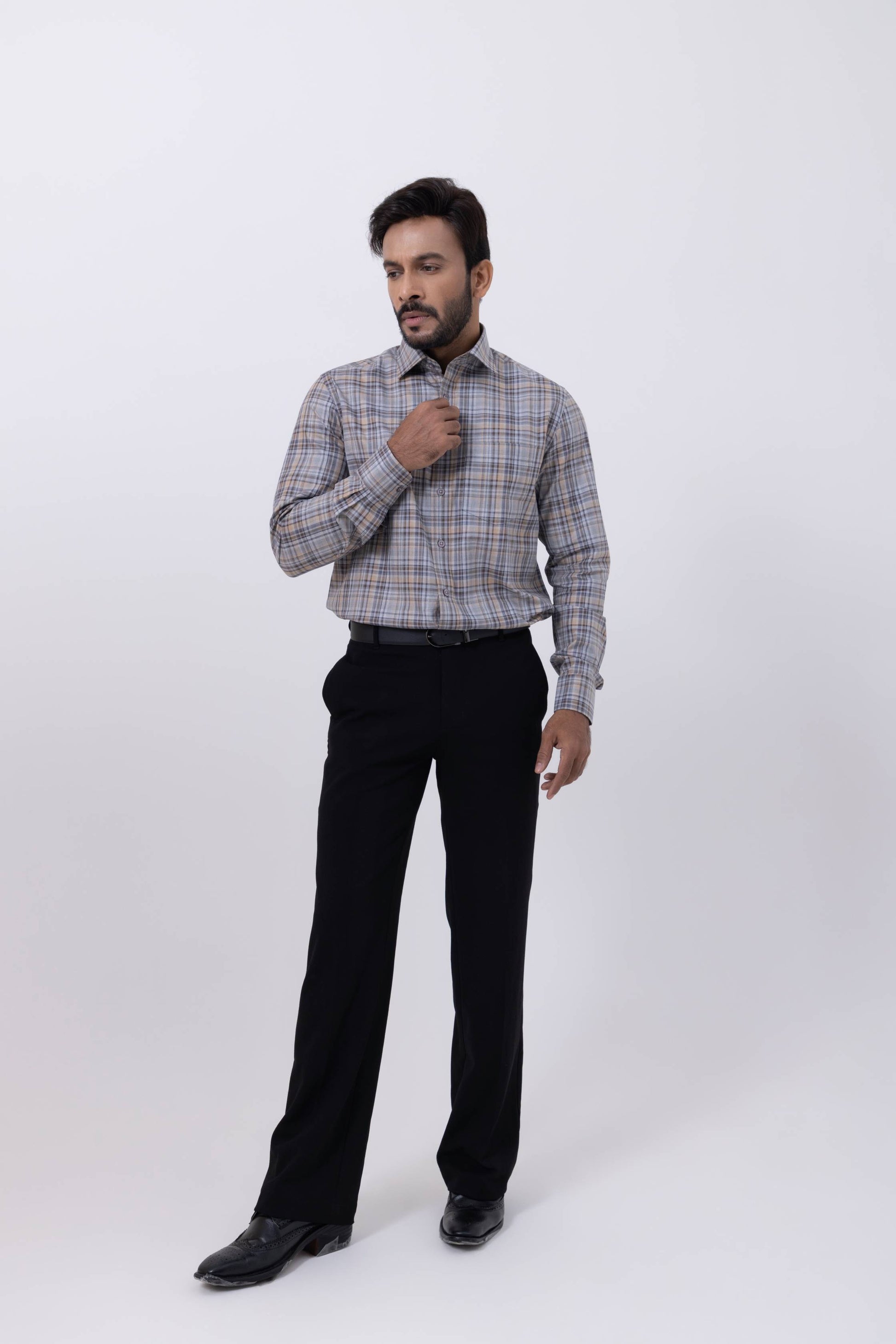 Man wearing a gray orange checked regular fit Giza cotton shirt, styled with black trousers, showcasing men's fashion.
